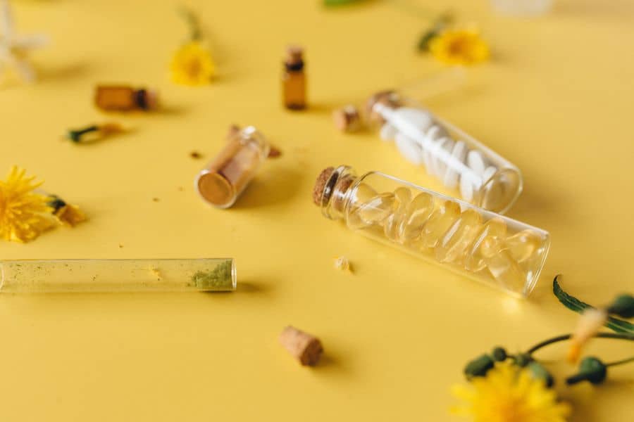 Različne tablete v stekleni embalaži na rumeni podlagi